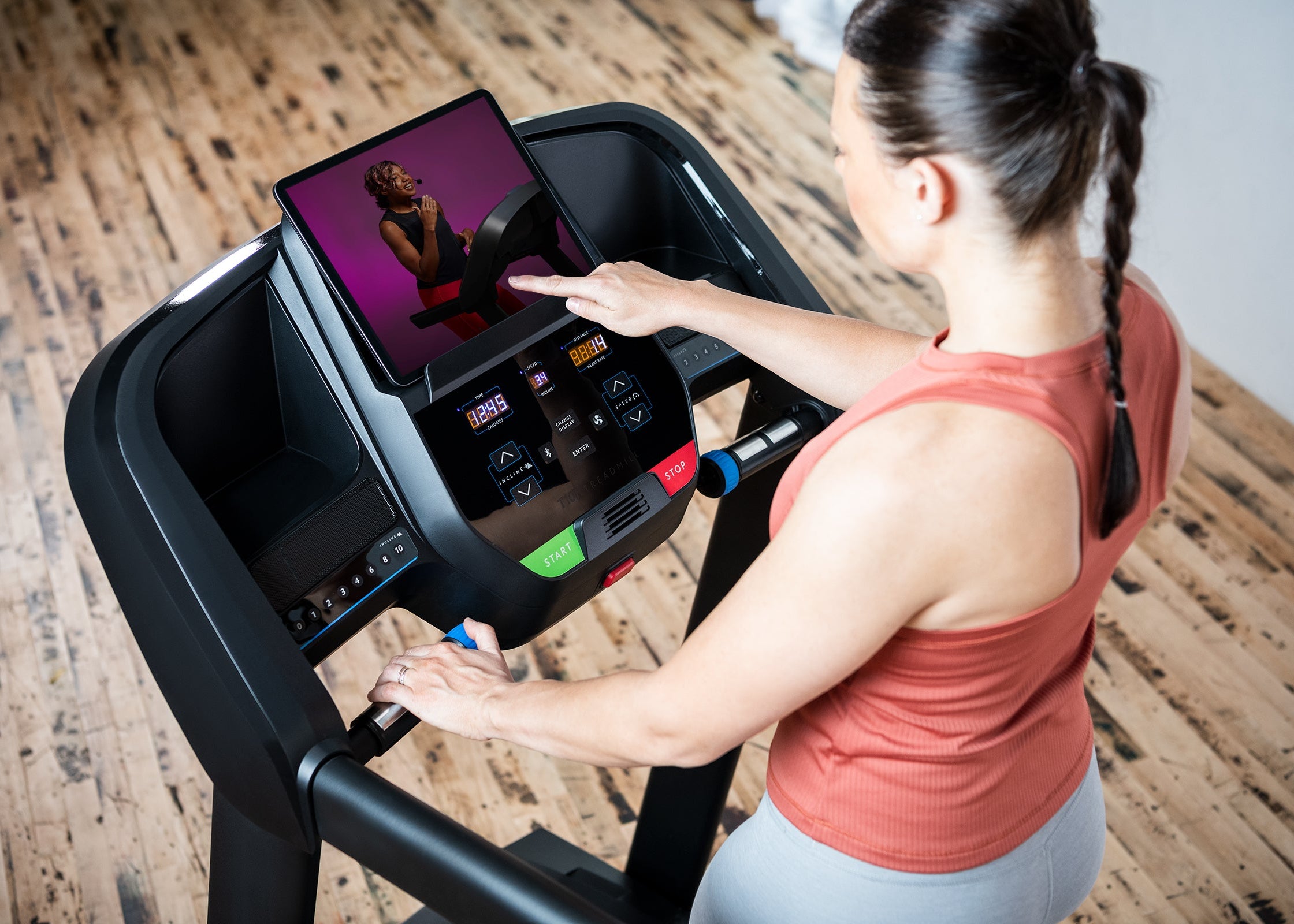 Woman using a treadmill with a tablet display in a home setting